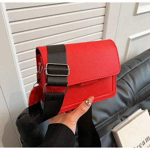 Detail of red PU leather crossbody bag featuring wide canvas strap and silver metal buckle