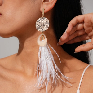 Close-up of bohemian white feather tassel earrings with golden hammered metal and resin