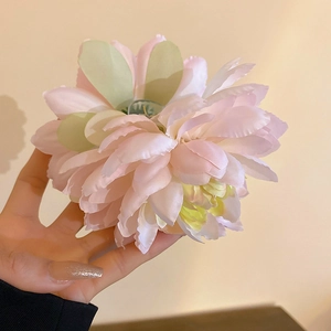 Detail of handmade woven fabric lotus hair claw with pink petals and green center