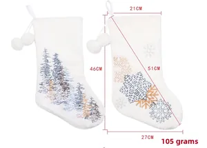 Detailed embroidery of snowflake and tree on white plush Christmas stockings with poms