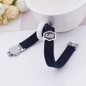 Black silicone germanium sports bracelet with metal buckle on a minimalist white desk