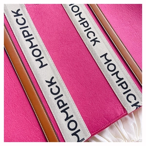 Macro detail of rose red felt tote bag with leather trim and branded woven handle strap
