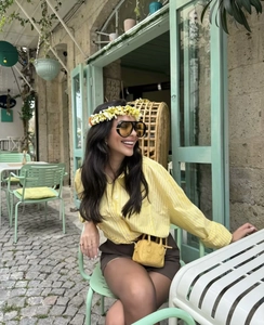 Close-up of yellow striped shirt and brown mini skirt set in a classic outdoor cafe setting