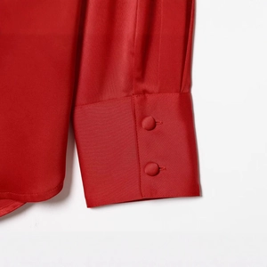 Detail of red satin blouse cuffs with elegant matching fabric-covered buttons