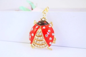 Macro detail of red beetle keychain featuring gold metal and clear rhinestone accents