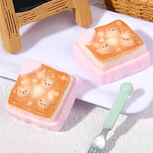 Detailed macro view of mini cat-themed resin toast charms with pink bases and small spoon