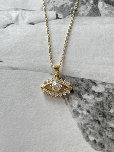 Detailed close-up of golden evil eye necklace pendant with zircon stones and fine chain