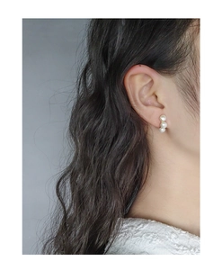 Gros plan de trois perles blanches verticales sur un clou d'oreille en or sur le mannequin