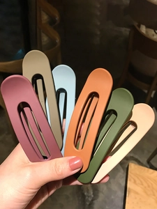 Detailed view of six matte oval hair clips in pastel pink, beige, blue, and green tones