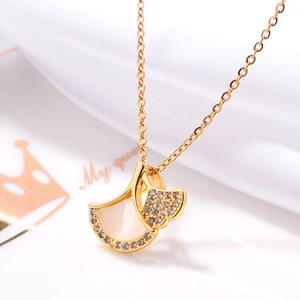 Macro view of ginkgo leaf necklace pendant with shell inlay and zircons on white silk