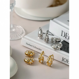Detailed view of 18k gold teardrop earrings with pearls and crystals on books