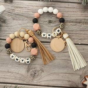 Silicone bead MAMA wristlet keychain with wooden disc and tassel on a natural wood surface