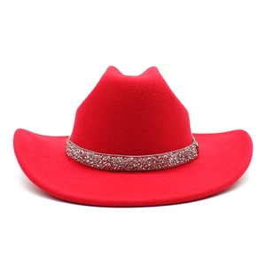 Detail of red felt cowboy hat featuring a sparkling rhinestone band on white background