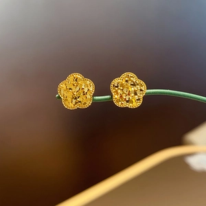 Nahaufnahme goldener Blumenohrstecker mit glitzerndem Finish und fünfblättrigem Design