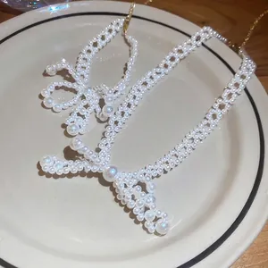 Ensemble collier et bracelet élégant en perles et acier inoxydable avec nœud sur une assiette