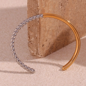 Close-up of twisted silver and smooth gold two-tone stainless steel open cuff bracelet
