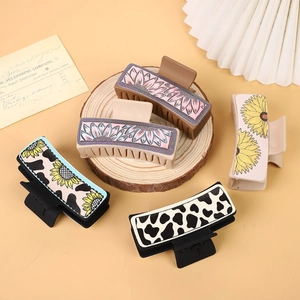 Detailed view of western style hair claws with sunflower and cow patterns on wood