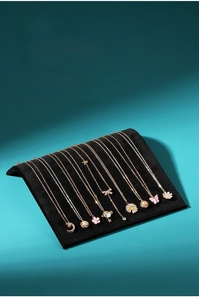Detail showing S-shaped black velvet jewelry display stand with multiple gold necklaces