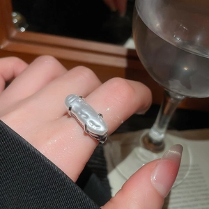 Close-up of irregular baroque pearl ring in silver claw setting on model's finger