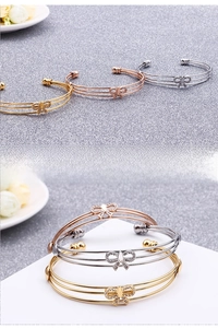 Détail de bracelets à trois couches en or, argent et or rose avec breloques papillon pavées