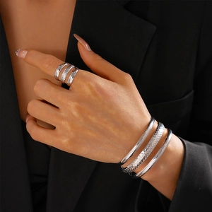 Detailed view of silver layered ring and bracelets set with textured finish on model