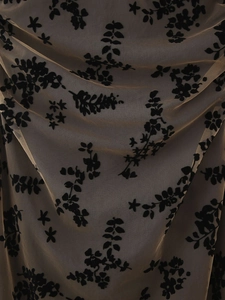 Détail macro du tissu mesh beige avec des motifs floraux floqués noirs et des textures