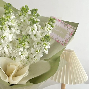 Close-up of white violet flower bouquet with a Thank You card and green floral packaging