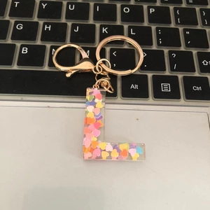Macro shot of resin letter L keychain with colorful heart glitter on a keyboard