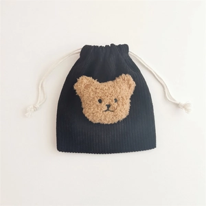 Close-up of black corduroy drawstring pouch with a brown plush bear patch and soft texture