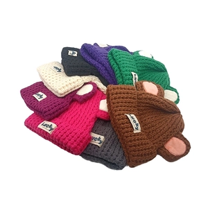 Pile de bonnets en tricot colorés avec oreilles d'ours et étiquette Lucky en nuances