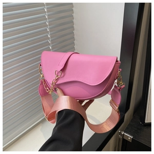 Detailed shot of a pink PU leather saddle bag with gold chain and wide fabric strap