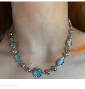 Detail of silver-tone link chain featuring light blue crystal beads worn on the neck