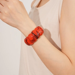 Detailed close-up of red acrylic geometric stretch bracelet with black marble texture on wrist