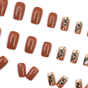 Caramel brown square press-on nails with black leaf patterns and gold foil flakes