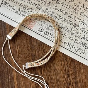 Detail of bohemian handmade woven belt with evil eye charm on vintage calligraphy background