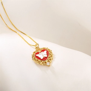 Detail of gold heart pendant with white butterfly on red enamel and tiny zircon crystal