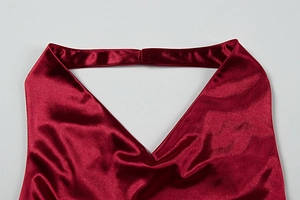 Detail of wine red satin halter neckline with smooth silky texture and glossy finish