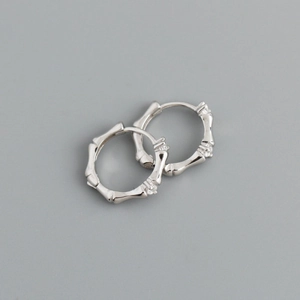 Dettaglio macro di orecchini in argento stile bambù con accenti di micro-pietre