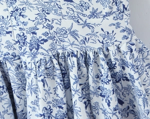 Detail of waist ruching and blue floral print on slim fit French style dress