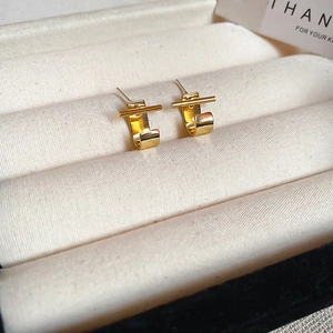 Close-up of elegant gold geometric C-shaped bar earrings in a jewelry gift box