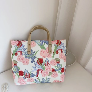 Macro detail of floral canvas tote bag with pink rose patterns and leather handles