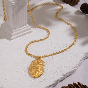 Détail macro d'un pendentif tête de Jésus doré sur une chaîne en O sur une pierre blanche