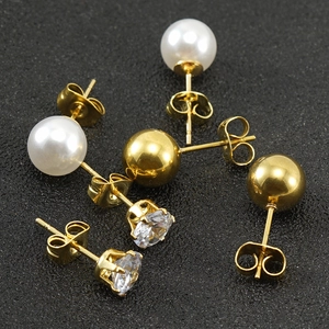 Three pairs of gold titanium earrings with pearls, zircons, and beads on a dark background