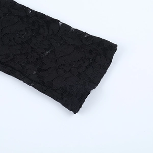 Vue macro détaillée du motif complexe de dentelle florale noire sur la manche de la combinaison