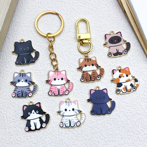 Detailed flat lay of colorful enamel cat charms and gold lobster clasps for DIY jewelry