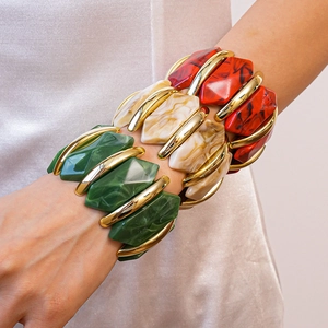 Détail de trois bracelets irréguliers en résine marbrée avec monture dorée sur le poignet