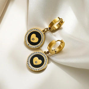 Elegant gold titanium earrings with black zircon heart drop on white silk background