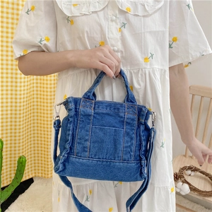 Detail of dark blue denim tote with orange stitching and detachable shoulder strap