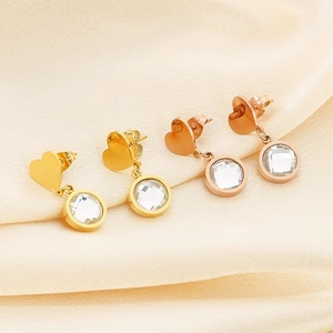 Detail shot of heart-shaped gold and rose gold earrings on beige satin background