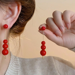 Vue détaillée de boucles d'oreilles pendantes perles rouges et chaîne dorée